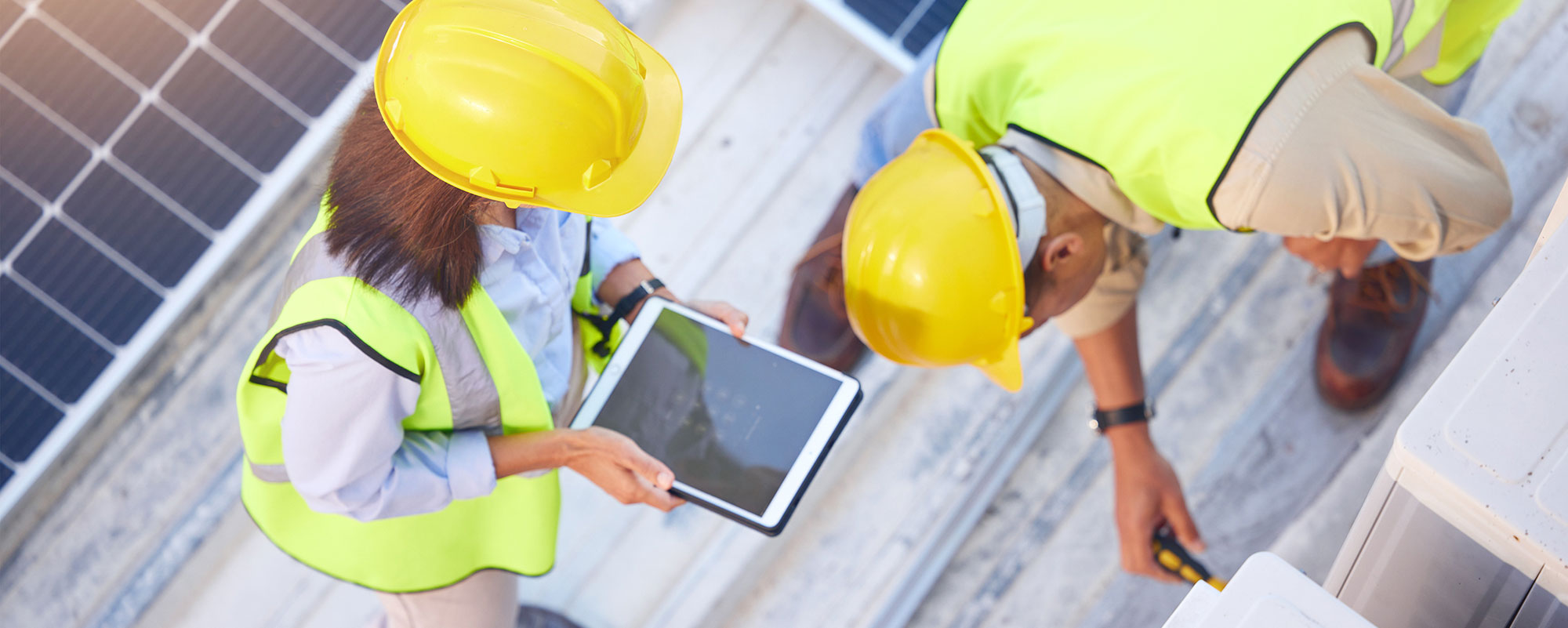Técnicos inspeccionando sistemas fotovoltaicos con una tableta para servicios ESG, sostenibilidad y monitoreo energético de activos inmobiliarios.