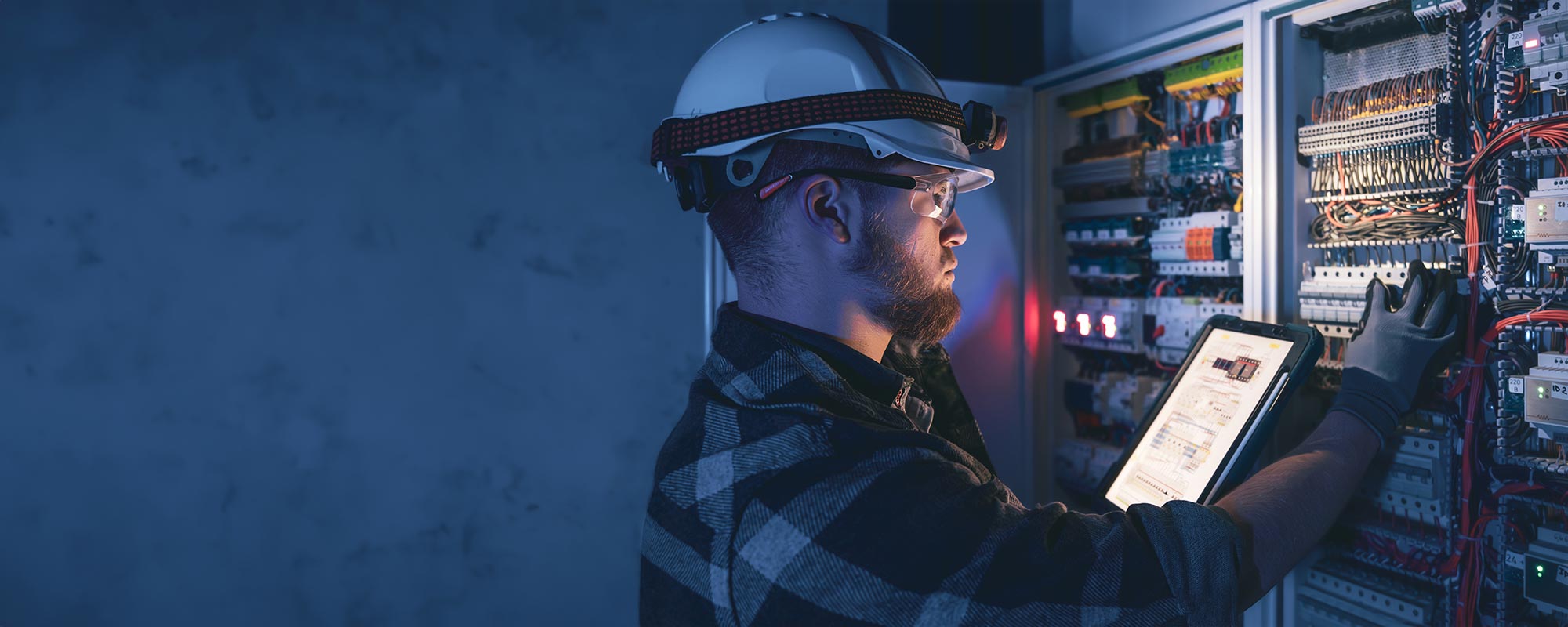 Tecnico specializzato verifica un quadro elettrico con tablet per servizi di energy management e monitoraggio degli impianti